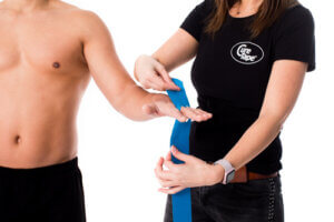 Physiotherapist applies medical tape to person on hand for treatment of carpal tunnel syndrome